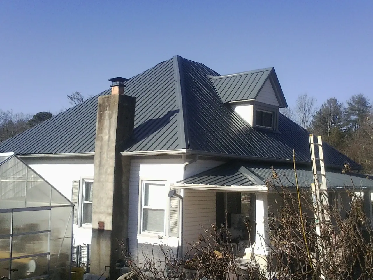 Dark blue standing seam metal roof on a white farmhouse with dormer — Slate & Tile Roof Repair by Roofing Brothers in Center Sandwich