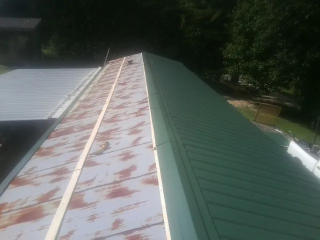 Old rusted panels beside newly installed green metal roofing — Wind Damage Roof Repair by Roofing Brothers in Center Sandwich