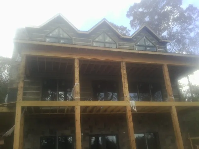 Dormers and porch framing on a large log home under construction — Roof Coating work by our crew in Center Sandwich