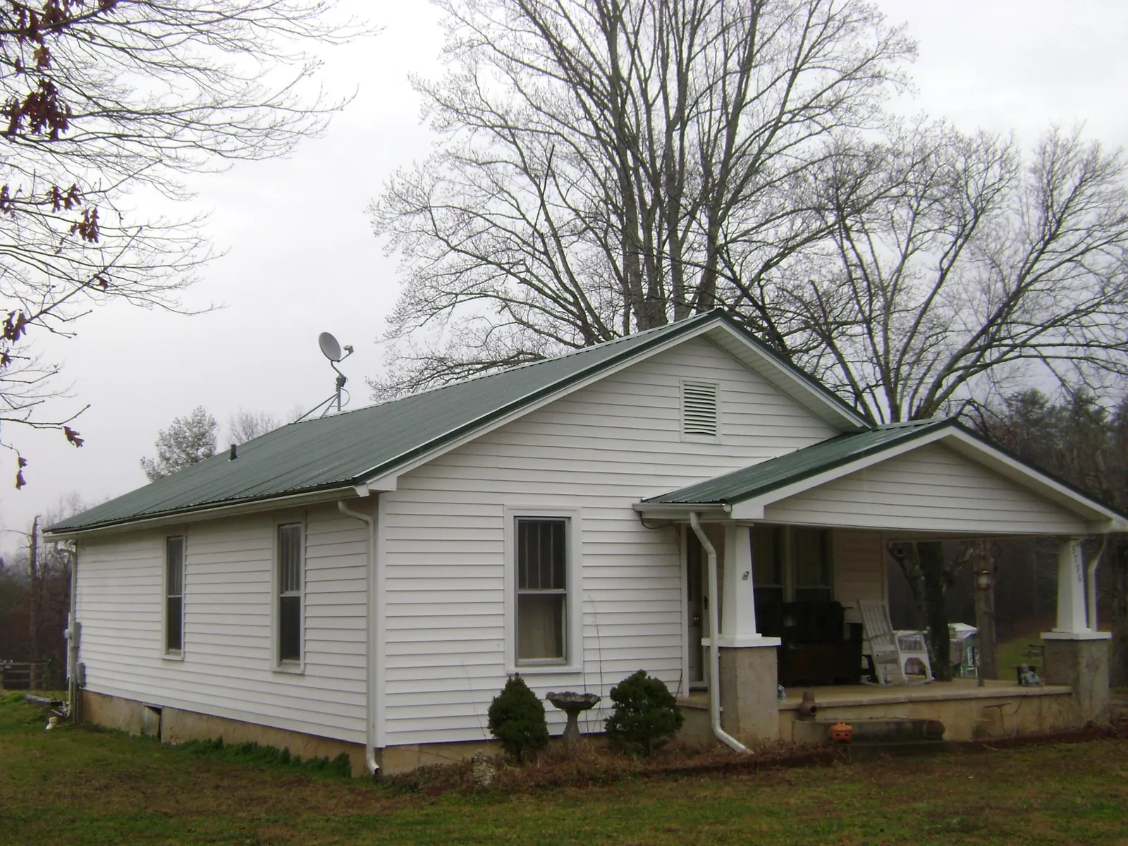 Green metal roof on a white bungalow with a side porch in Center Sandwich