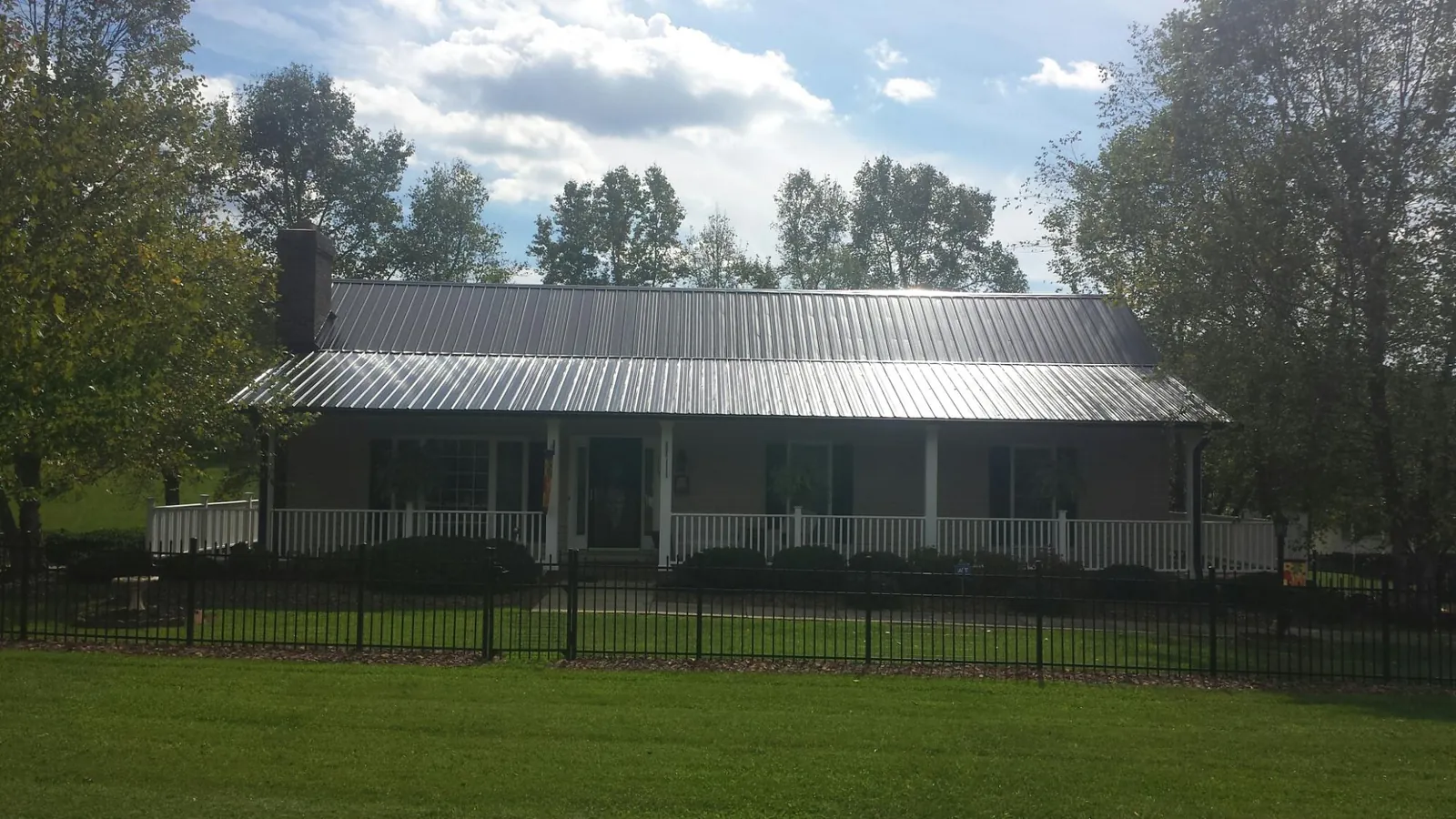 Gray metal roof on a brick ranch with a full width front porch — Gutter Guard Installation work by our crew in Center Sandwich