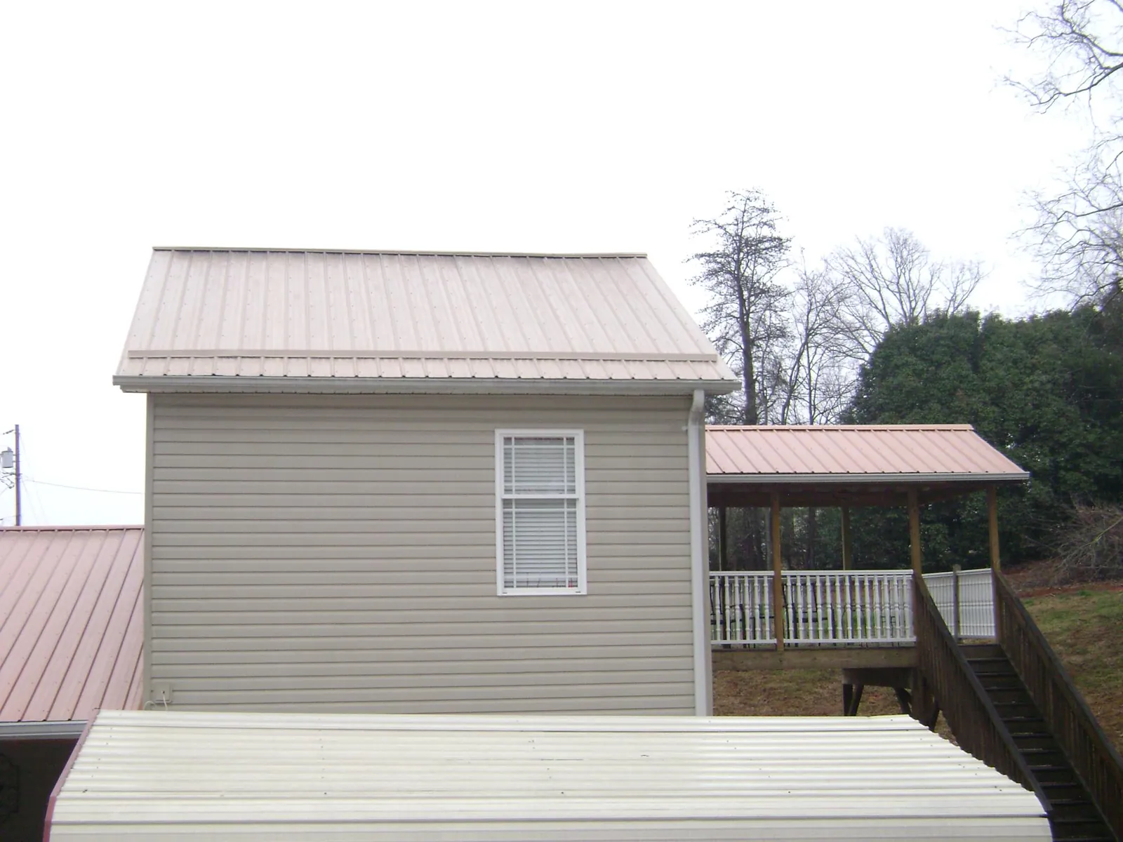 Tan metal roofs on a two story addition and attached porch, from a Roof Replacement job in Center Sandwich
